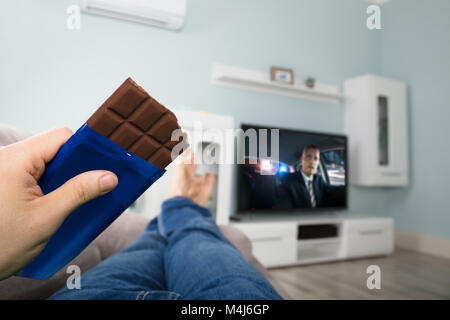 Close-up d'une personne bénéficiant de chocolat en regardant Film à la télévision à la maison Banque D'Images