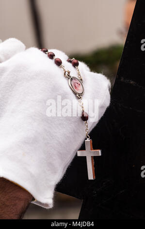 Détail de la main d'un pénitent avec un chapelet, compter les billes en priant. Banque D'Images