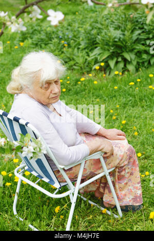 La grand-mère au jardin sous un pommier en fleurs Banque D'Images