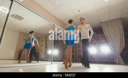 Beau jeune homme et femme danser et pratiquer la danse latine en costumes dans le studio Banque D'Images