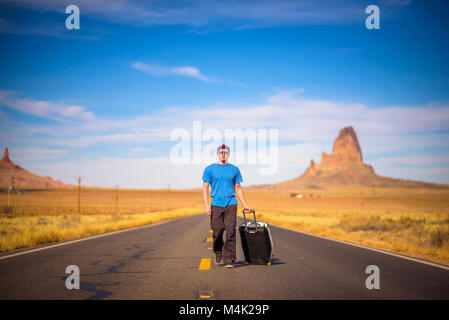 Jeune voyageur avec une valise de marcher sur une route en Arizona Banque D'Images