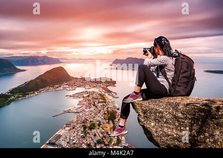 Photographe Nature touriste avec appareil photo shoots en se tenant sur le haut de la montagne. Aksla à la ville d'Alesund , la Norvège. Banque D'Images