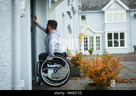 Homme handicapé faire sonner la cloche de porte Banque D'Images