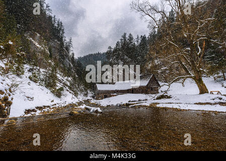 Ancien moulin à eau en bois en hiver avec la neige qui tombe Banque D'Images