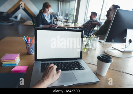 Businessman using laptop alors que collègues having discussion Banque D'Images