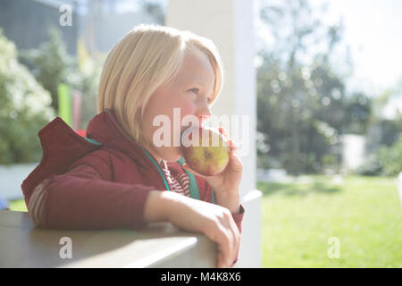 Boy eating apple dans le porche Banque D'Images