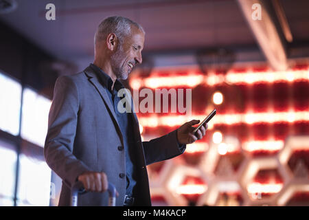 Businessman using smart phone en entrant dans l'hôtel Banque D'Images