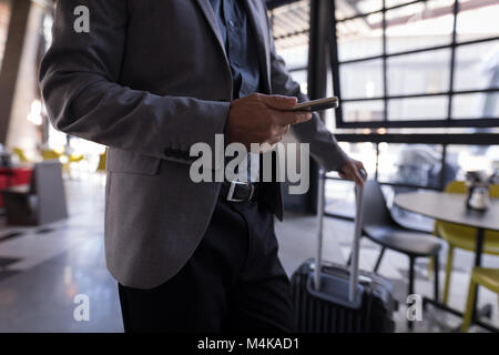 Businessman using smart phone en entrant dans l'hôtel Banque D'Images