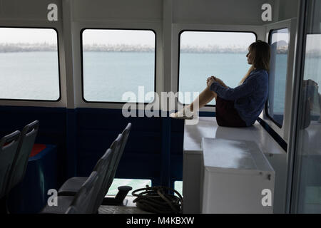 Femme assise près de fenêtre en bateau de croisière Banque D'Images