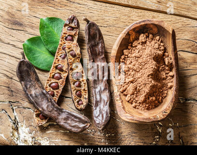 Gousses de caroube et caroubes sur la table en bois. Banque D'Images