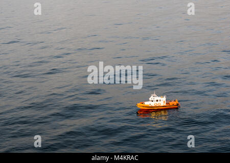 Petite réponse emegency bateau flottant autour d'une plate-forme pétrolière pendant le coucher du soleil Banque D'Images