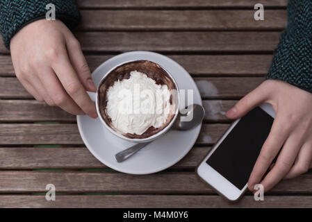 Femme ayant un cappuccino au café en plein air Banque D'Images