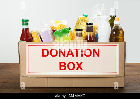 Différents aliments en boîte de donation sur table en bois Banque D'Images