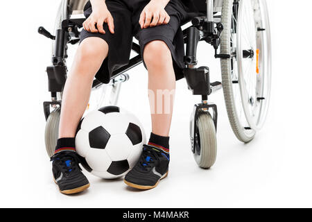 Mobilité enfant garçon assis sur fauteuil roulant holding soccer ball Banque D'Images