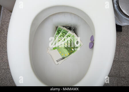 Portrait d'une centaine de billets d'euros à la cuvette des toilettes Banque D'Images