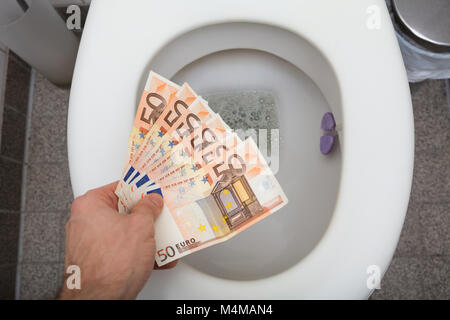 Portrait de la main d'un homme jetant cinquante euros en toilettes Banque D'Images