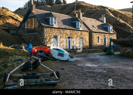 Village balnéaire Crovie, Aberdeenshire, Scotland, UK, avec des chalets à terre et sur l'avant des bateaux rive Banque D'Images