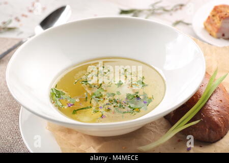 Soupe au poulet avec du pain en plaque blanche sur fond de bois blanc Banque D'Images