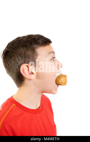 Young caucasian teenage boy eating a pork pie Banque D'Images