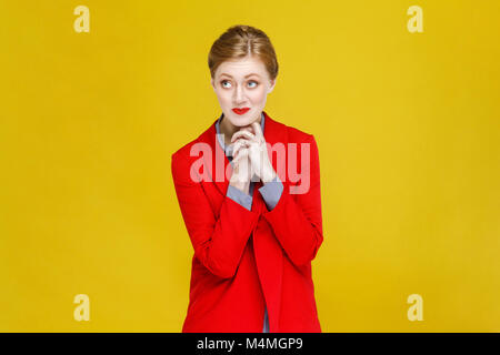 Ginger red head femme en costume rouge et souhaite de rêver. Studio shot, isolé sur fond jaune Banque D'Images