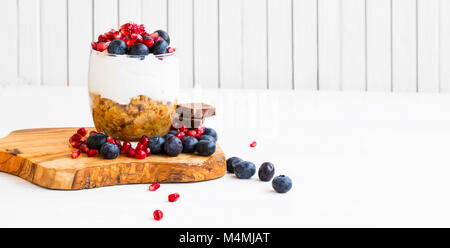 Le Tiramisu dans un verre avec la crème de mascarpone, bleuets et grenade fruits, sweet effiloche sur planche de bois Banque D'Images