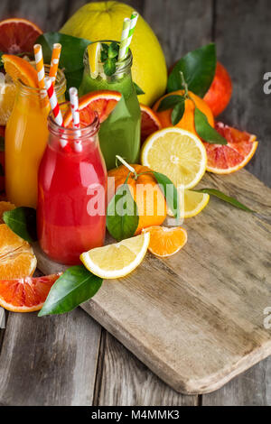 Fresh orange, jus d'orange sanguine et de limonade fait maison dans de petites bouteilles sur la vieille table en bois. Copie espace arrière-plan. Banque D'Images