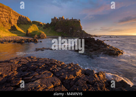 Coucher du soleil de la côte sous le château de Dunluce, comté d'Antrim, en Irlande du Nord. Banque D'Images