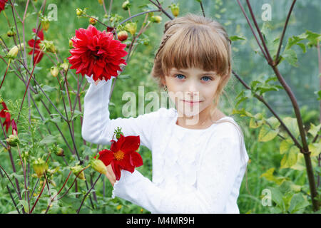 Petite fille aux fleurs dans le jardin en été Banque D'Images