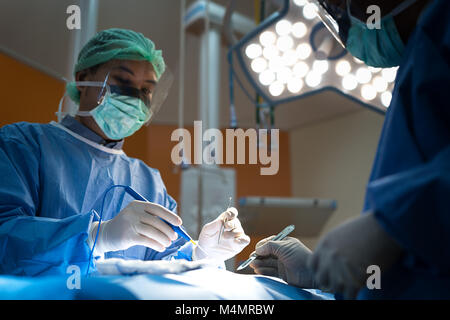 Médecin d'Asie et d'un assistant dans la salle d'opération pour chirurgie vasculaire veineux en chirurgie clinique à l'hôpital. Banque D'Images