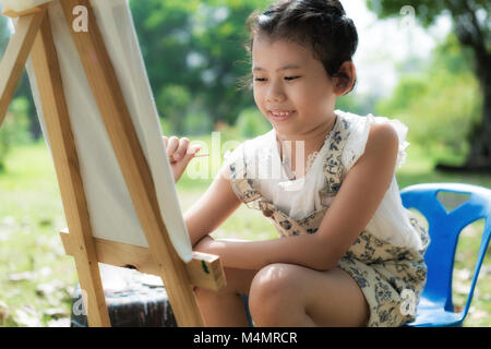 Les enfants asiatiques ou cute kid girl painting couleur de l'eau sur le papier et la nature prairie au jardin ou parc public pour le plaisir et l'éducation préscolaire en vacances r Banque D'Images