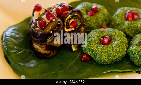 Rouleaux de l'aubergine avec un remplissage de noix, Georgian snack 'pkhali" d'épinards avec des herbes et des graines de grenade, sur la feuille de chard Banque D'Images