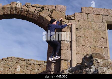 Jeune homme 'Roof-topping' les ruines de nouveau Slains Castle, Bay Cruden, Aberdeenshire, Scotland, UK. Sous le soleil d'Hivers 24. Banque D'Images