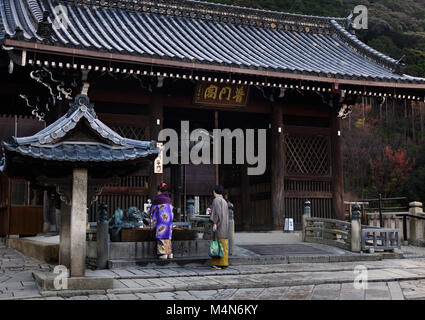 Habillé traditionnellement couple japonais se laver les mains à chozubachi, bassin de nettoyage, à l'entrée de Todoroki-mon gate le Kiyomizu-dera, temple bouddhiste Banque D'Images