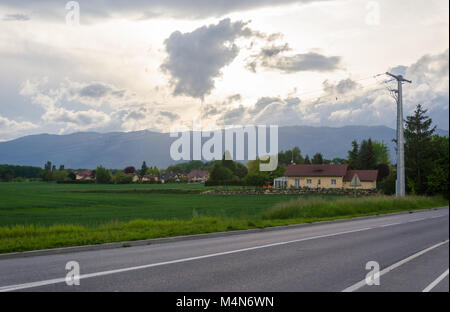 Scène paisible campagne française avec de simples maisons d'époque et de vastes prairies dominé par les Alpes à Prévessin-Moëns, France. Banque D'Images