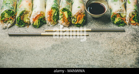 Helathy cuisine asiatique. Rouleaux de papier de riz de printemps végétaliennes avec légumes, sauce soja, baguettes sur fond de béton, copiez l'espace. Manger propre, dietin Banque D'Images