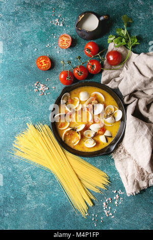 Dans une sauce à la crème de tomate Vongole pour les pâtes en fonte poêle avec du textile et ingrédients pour la cuisson des spaghettis au-dessus sur fond texture turquoise. T Banque D'Images