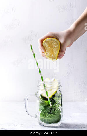 Ingrédients pour agiter et épinards vert smoothie pomme en pot Mason avec retro tube cocktail anh mains avec jus de citron plus de texture backgrou blanc Banque D'Images