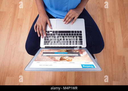 Image composite de mid section of female executive using laptop while sitting on wooden floor Banque D'Images