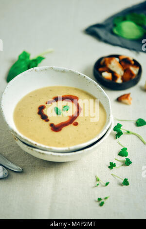 Soupe aux lentilles turque arrosée d'une sauce rouge servi dans un bol en céramique blanc photographié à partir de la vue de face. Accompagner de croûtons et d'herbes. Banque D'Images