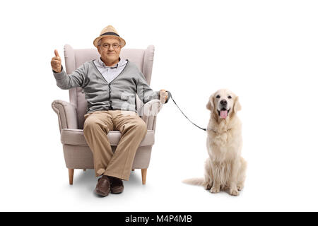 Homme mature avec un labrador retriever chien assis dans un fauteuil et de faire un pouce vers le haut signe isolé sur fond blanc Banque D'Images