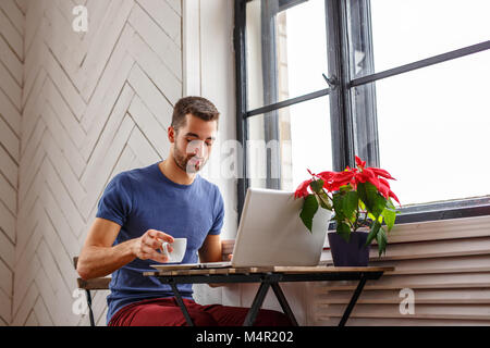 Homme barbu de boire du café et à l'aide d'un ordinateur portable. Banque D'Images