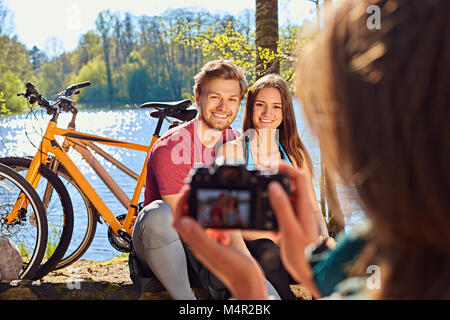 Une femme à prendre des photos de couple sportif après balade à vélo dans une forêt. Banque D'Images