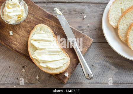 Le beurre et le pain pour le petit-déjeuner, avec couteau sur fond de bois rustique, vue du dessus Banque D'Images