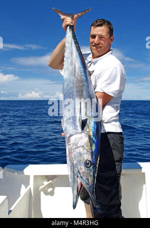 La pêche en haute mer, pêche au gros. prise de poissons. Lucky fisherman holding un énorme poisson wahoo Banque D'Images