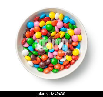 Bonbons de chocolat colorés comprimés dans un bol isolé sur fond blanc. Vue d'en haut Banque D'Images