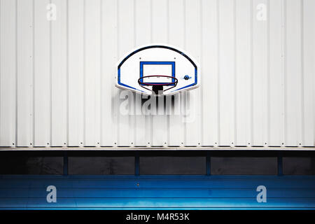 Panier de basket-ball fixé sur un mur blanc au-dessus de la porte de garage bleue. Banque D'Images