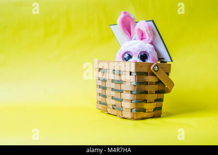 Lapin de Pâques avec panier sur un fond jaune. Banque D'Images