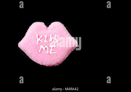 Valentines Heart shaped candies avec 'Kiss me' sur fond noir. Banque D'Images