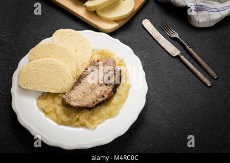 La cuisine traditionnelle tchèque, la viande de porc et de choux dumpings sur table en pierre sombre Banque D'Images