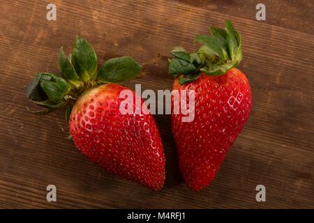 Fraises rouges frais tourné à partir de juste au-dessus en studio sur fond de bois brun Banque D'Images